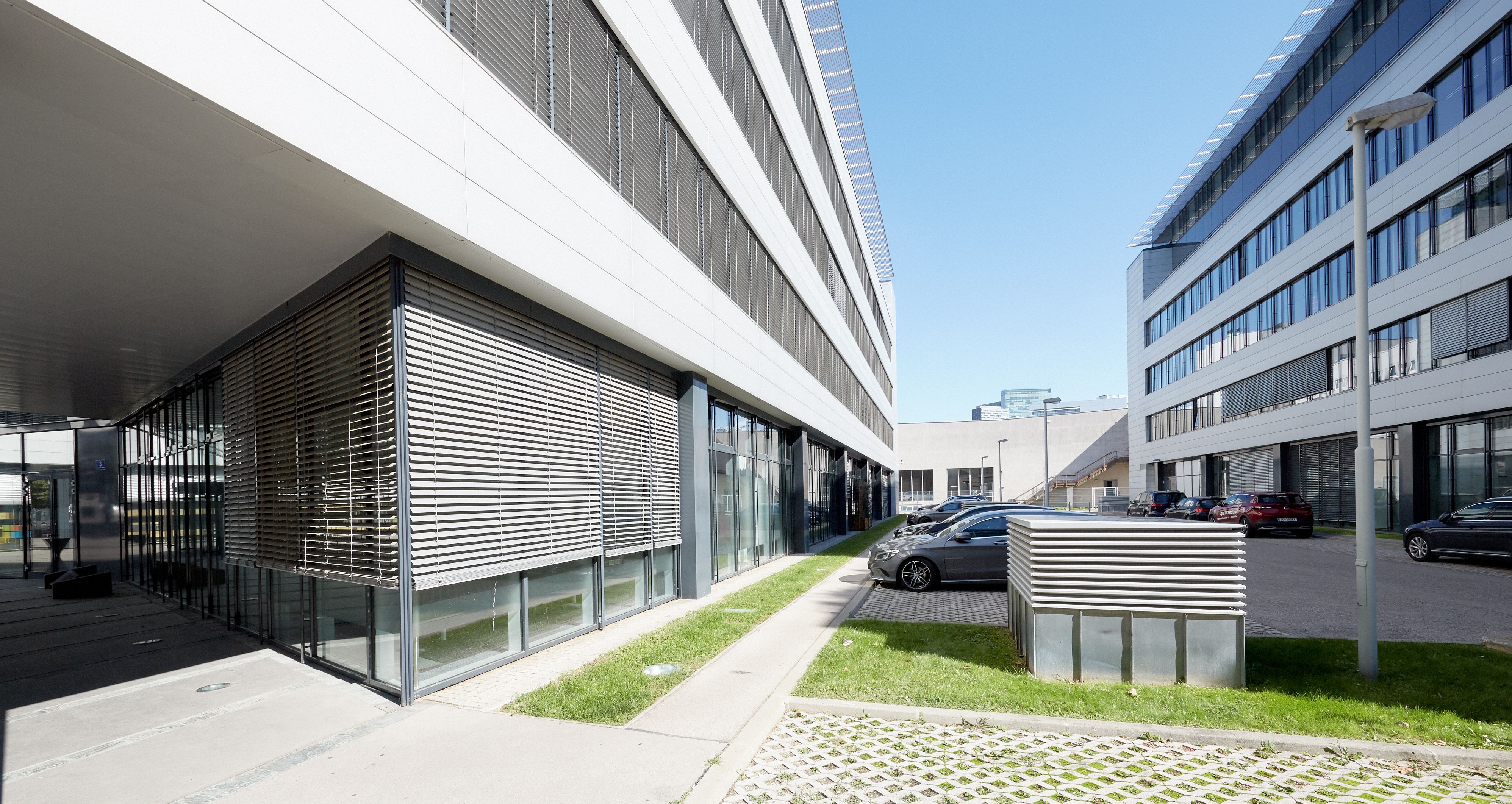 Foto: linker und rechter Hand zwei gegenüberliegende moderne Bürogebäude mit Alu-Glasfassade