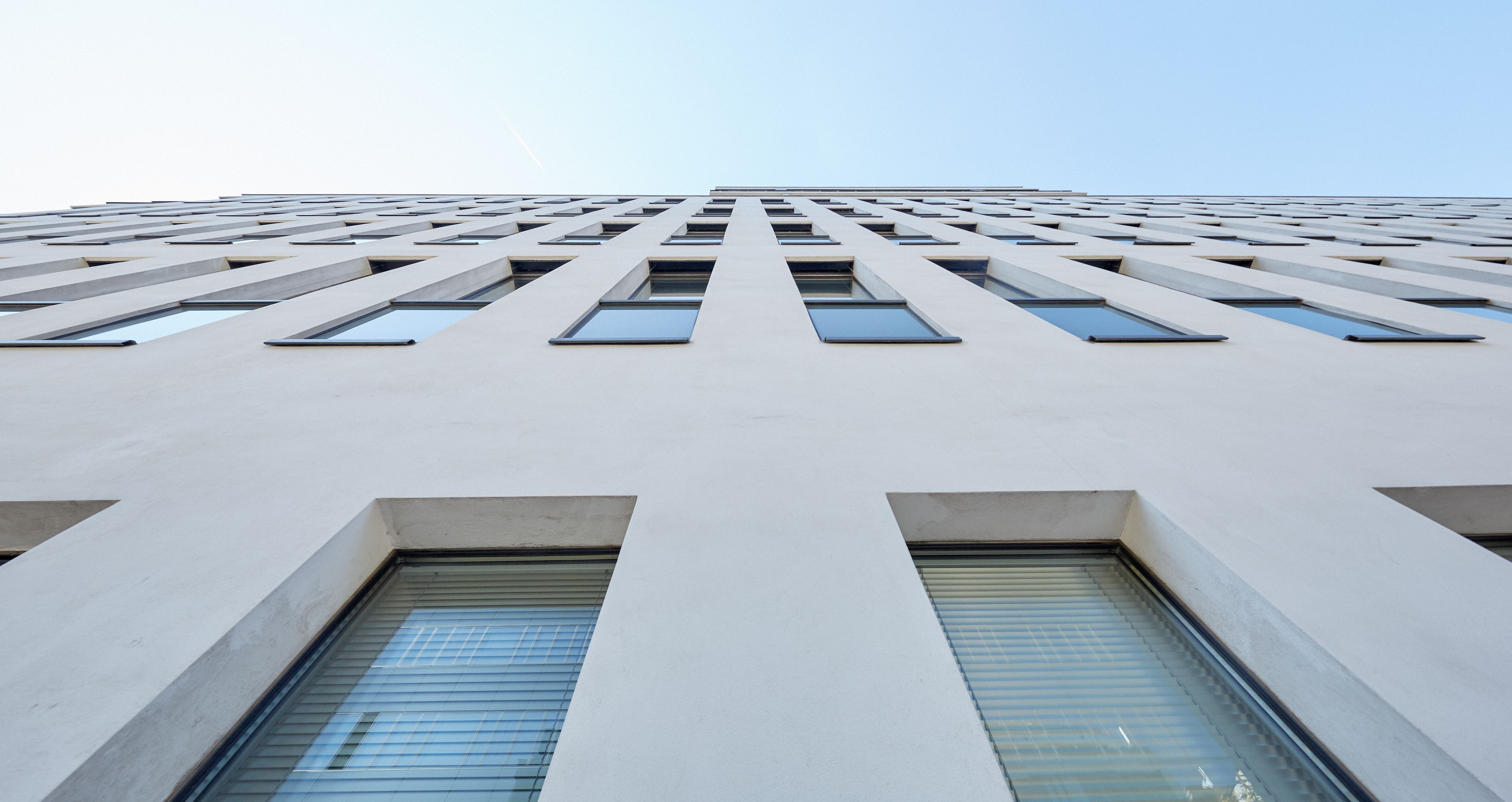 Foto: moderne Fassade mit hochgezogenen, schmalen Fenstern; aus unmittelbarer Nähe von unten in spitzem Winkel aufgenommen